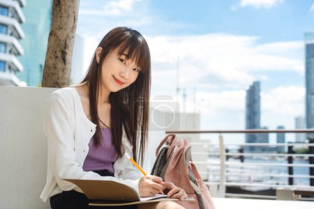 Photo for College people education lifestyle on day time concept. Single young adult asian student woman sit and studying with notebook at campus area. - Royalty Free Image