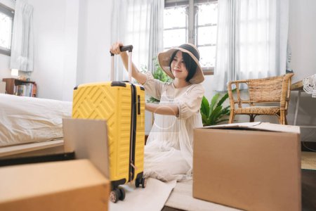 Photo for People moving house to new home or apartment concept. Happy smile woman begin relocation in cozy style room with window. Girl with short hair and casual clothing using luggage. - Royalty Free Image