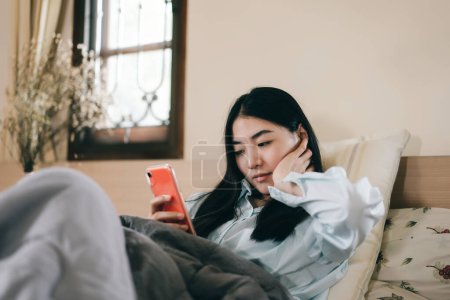 Young adult single woman using smartphone in the moring for modern technology app for mental health at home.