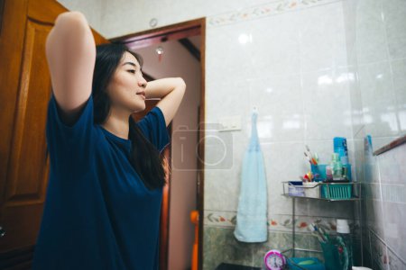 Téléchargez les photos : Jeune femme asiatique adulte pratique l'auto et vérifier par miroir dans la salle de bain à la maison. Santé mentale maintenir le mode de vie après le réveil concept. - en image libre de droit