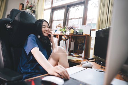 Téléchargez les photos : Stay at home office lifestyle concept. Happy smile young adult freelancer asian woman wear headset in workplace space with window light on day. Still life with modern digital online media. - en image libre de droit