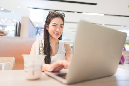 Photo for People doing freelance digital nomad job concept. Happy smile face young asian entrepreneur woman sitting indoors cafe with laptop. After shopping city lifestyles. - Royalty Free Image