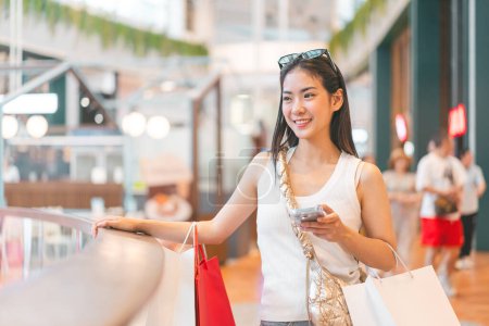 Photo for People city lifestyles with buying shopping consumerism. Young adult asian woman using smartphone. Happy smile face sitting at indoors department store. - Royalty Free Image