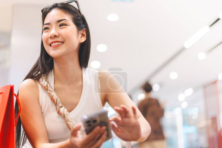 Photo for People city lifestyles with buying shopping consumerism. Young adult asian woman using smartphone. Happy smile face sitting at indoors department store. - Royalty Free Image