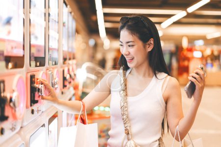Photo for People city lifestyles with buying shopping consumerism. Young adult asian woman play gashapon at game center. Happy smile face at indoors department store. - Royalty Free Image