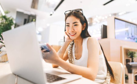 Photo for People doing freelance digital nomad job concept. Happy smile face young asian woman sitting indoors cafe on table with laptop. Influencer gen z modern lifestyles. - Royalty Free Image