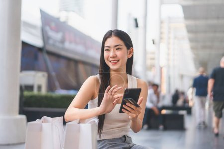 Photo for Elegant people city lifestyles with buying shopping consumerism. Young adult asian woman using smartphone. Happy smile face sitting at department store. - Royalty Free Image