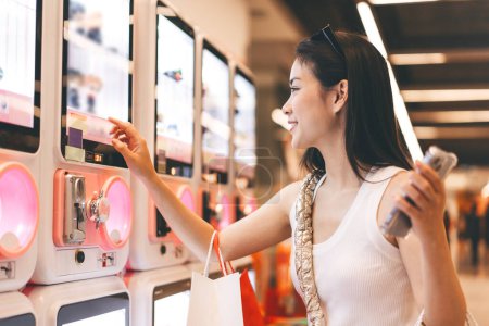 Photo for People city lifestyles with buying shopping consumerism. Young adult asian woman play gashapon at game center. Happy smile face at indoors department store. - Royalty Free Image