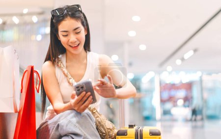 Photo for Elegant people city lifestyles with buying shopping consumerism. Young adult asian woman using smartphone. Happy smile face sitting at indoors department store. - Royalty Free Image