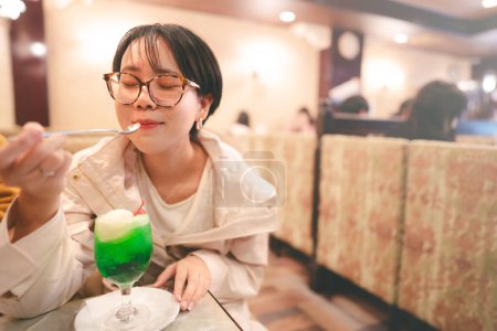 Photo for People relax in kissaten japan style retro coffee shop. Young adult asian woman drinking icecream melon soda trendy japanese teenager people menu. - Royalty Free Image