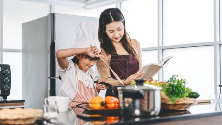 Téléchargez les photos : Joyeux asiatique famille mère et fille cuisine dans la cuisine. Préparation des repas pour le dîner. Recette maison. Loisirs mode de vie ensemble enfant avec parent à la maison. - en image libre de droit