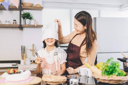 Photo for Happy asian family mother and daughter cooking in kitchen. Preparation food for dinner meal. Homemade recipe. Leisure lifestyles together child with parent at home. - Royalty Free Image