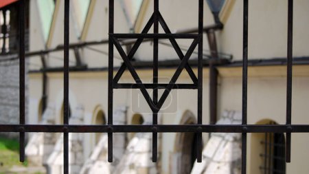 Photo for Star of David on metal fence. In the background is the old synagogue in the Jewish quarter in Kazimierz. Cracow, Poland. - Royalty Free Image