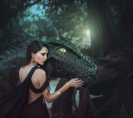 Fantasy woman evil dark queen witch hugs dragon, touching with hands head. Girl mistress tamed monster, concept of dominance control. black dress open sexy back, fashion model, golden jewelry diadem