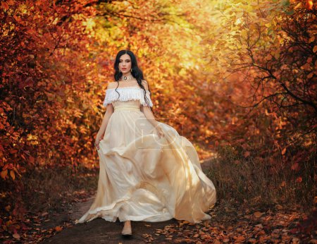 Foto de arte mujer de fantasía reina caminando en bosque de otoño gótico, vestido de estilo vintage blanco. Chica princesa belleza cara largo cabello ondulado, elegantes hombros abiertos desnudos sexy. Color rojo naranja amarillo árbol oscuro
