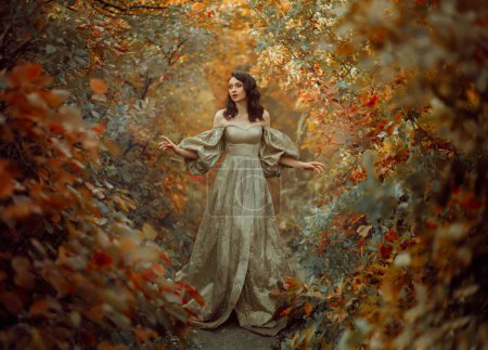 Queen fantasy woman walks in path mystical autumn forest. Orange Gold red foliage fairy tale scenery trees. Happy smiling Princess girl. Vintage long golden dress, puffy sleeves. Sexy medieval lady