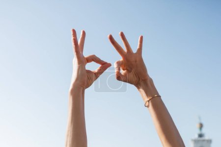 Foto de Vista recortada de la mujer mostrando gesto bien con el cielo en el fondo - Imagen libre de derechos