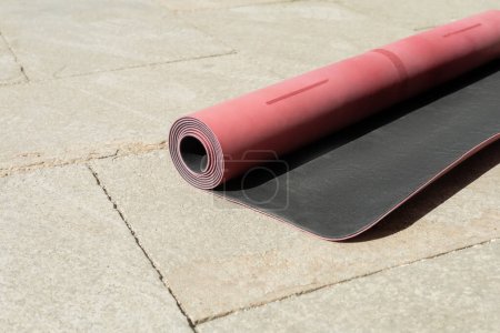 rosafarbene Fitnessmatte mit Schatten auf Asphalt-Bürgersteig auf städtischer Straße bei sonnigem Sommerwetter 