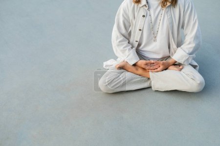 Photo for Partial view of barefoot man in white clothes meditating in lotus pose on stadium - Royalty Free Image