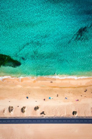Téléchargez les photos : Vue aérienne de la plage avec route asphaltée dans le parc Corralejo, Fuerteventura. Plage (Grandes Playas de Corralejo) et route sur Fuerteventura, Îles Canaries, Espagne. Belle eau turquoise et sable blanc. - en image libre de droit