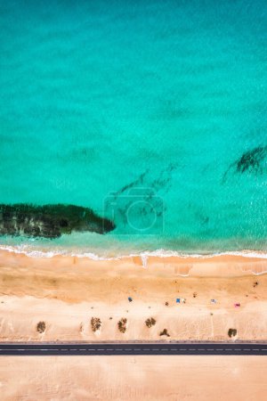 Téléchargez les photos : Vue aérienne de la plage avec route asphaltée dans le parc Corralejo, Fuerteventura. Plage (Grandes Playas de Corralejo) et route sur Fuerteventura, Îles Canaries, Espagne. Belle eau turquoise et sable blanc. - en image libre de droit