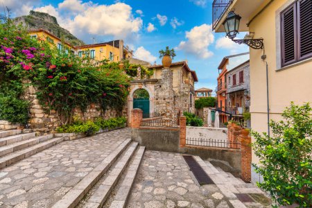 Hermoso casco antiguo de Taormina con pequeñas calles, flores. Arquitectura con arcos y pavimento viejo en Taormina. Colorida calle estrecha en el casco antiguo de Taormina. Sicilia, Italia. 