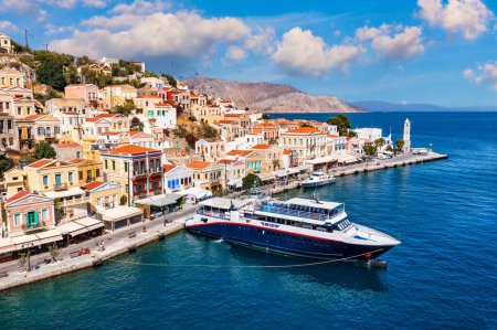 Photo for View on Symi (Simi) island harbor port, classical ship yachts, houses on island hills, Aegean Sea bay. Greece islands holidays vacation travel tours from Rhodos island. Symi, Greece,  Dodecanese. - Royalty Free Image