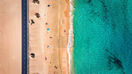 Foto de Vista aérea de playa con carretera asfaltada en el Parque Corralejo, Fuerteventura. Playa (Grandes Playas de Corralejo) y carretera en Fuerteventura, Islas Canarias, España. Hermosa agua turquesa y arena blanca. - Imagen libre de derechos