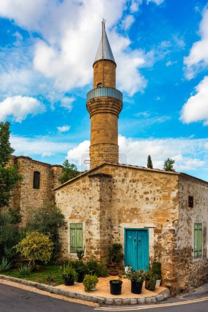 Un petit bâtiment avec une porte bleue se trouve en face d'une grande mosquée avec une haute tour à Nicosie, Chypre. Belle rue avec une architecture ancienne à Nicosie, Chypre.