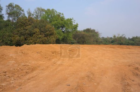 Red mud land with greenery and blue sky in the background