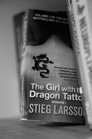Téléchargez les photos : Un gros plan vertical en niveaux de gris du roman The Girl With The Dragon Tattoo de Stieg Larsson sur une étagère. - en image libre de droit