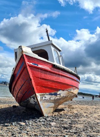 Téléchargez les photos : Plan vertical d'un vieux bateau endommagé à la plage sous les nuages - en image libre de droit
