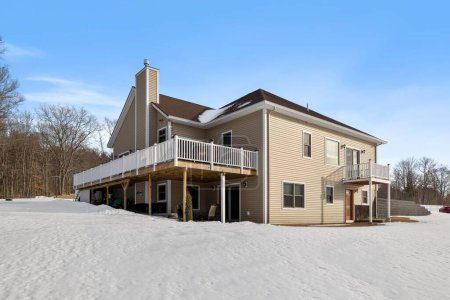Téléchargez les photos : Un gros plan d'une belle maison moderne avec une grande cour recouverte de neige contre une forêt aux États-Unis - en image libre de droit