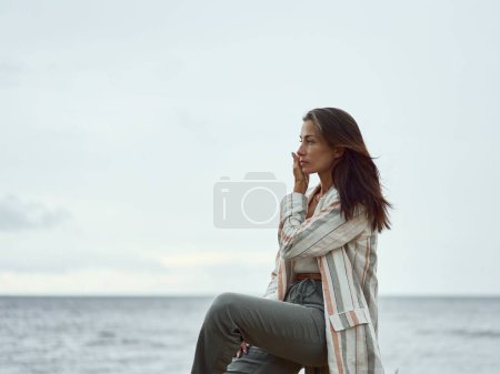 Téléchargez les photos : Une jolie femme blanche caucasienne posant sur le rivage par une journée nuageuse - en image libre de droit