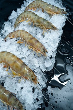 Téléchargez les photos : Un plan vertical de crevettes fraîches crues sur de la glace exposée dans un marché - en image libre de droit