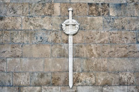 Photo for A closeup of a white sword with a wreath on the stone wall at the Brethren Cemetery in Riga, Latvia - Royalty Free Image