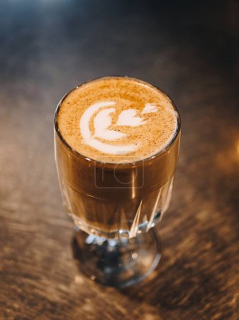 Foto de Una toma vertical de arte latte en una taza de café colocada sobre una mesa de madera. - Imagen libre de derechos