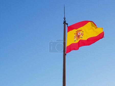 Photo for A closeup of a flag of Spain flowing in the air with a clear sky in the background - Royalty Free Image