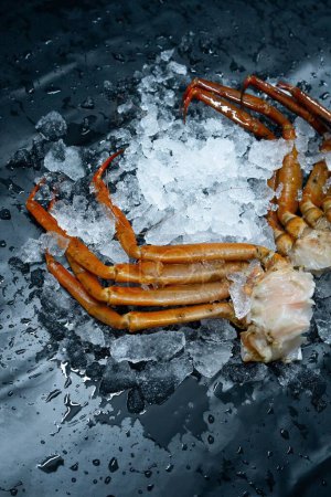 Téléchargez les photos : Plan vertical de morceaux tranchés d'un crabe sur glace isolés sur un fond sombre - en image libre de droit
