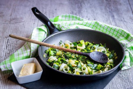Téléchargez les photos : Un gros plan de légumes frits et d'oignons dans une casserole avec du beurre près de - en image libre de droit