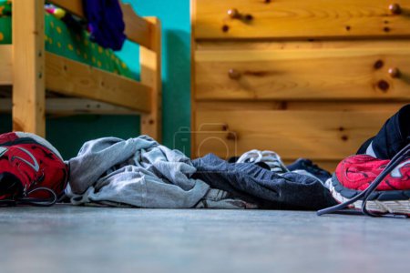 Téléchargez les photos : Quelques vêtements jetés au sol d'une pièce désordonnée - en image libre de droit