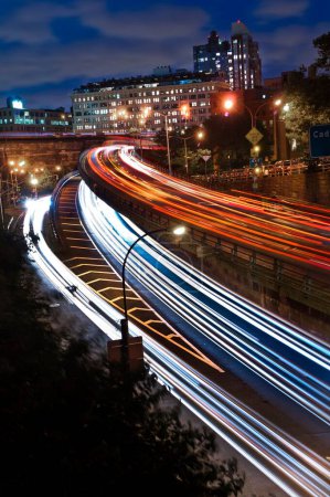 Téléchargez les photos : Une longue exposition verticale des feux des véhicules dans les rues d'une ville urbaine la nuit - en image libre de droit