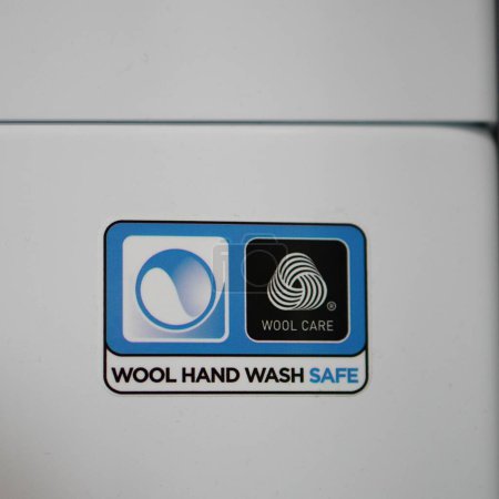 Photo for A vertical closeup of a Wool Hand Wash Safe sticker on a laundry machine. - Royalty Free Image