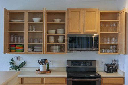 Téléchargez les photos : Une cuisine avec armoires en bois ouvertes avec vaisselle bien organisée, une cuisinière LG et un micro-ondes intégré - en image libre de droit