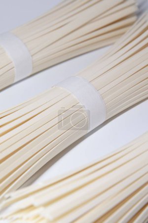 Photo for A vertical closeup of wooden bamboo sticks for skewer on a white background - Royalty Free Image