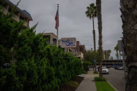 Photo for The Inn by the Sea hotel on Fay avenue with palm trees and American flag on a cloudy day - Royalty Free Image