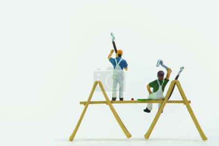 Foto de Las figuras en miniatura de los trabajadores de la construcción pintando las paredes sobre un fondo blanco - Imagen libre de derechos