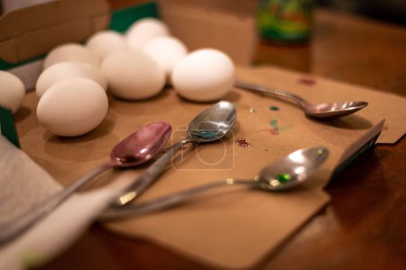 Foto de Un primer plano de cucharas con manchas de colores junto con huevos frescos en una superficie marrón - Imagen libre de derechos