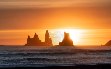 Téléchargez les photos : Les silhouettes des stocks marins de Reynisdrangar à Vik Islande contre le coucher de soleil doré brillant - en image libre de droit