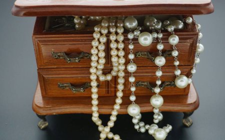 Foto de Un primer plano de collares de perlas falsas extra largas en una baratija vintage de madera - Imagen libre de derechos